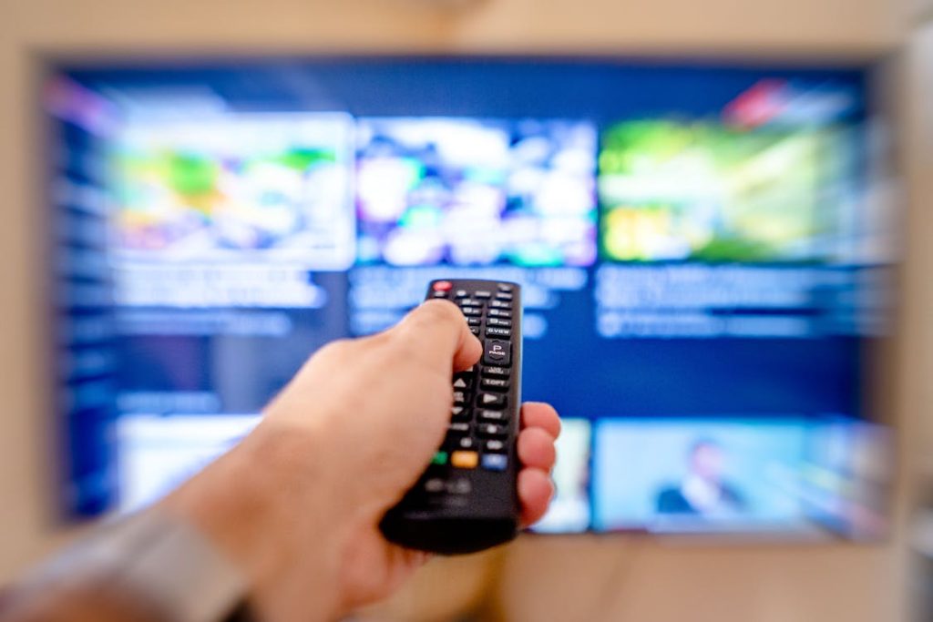 Persona usando control remoto para elegir plan IPTV